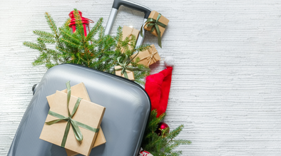 Gray suitcase filled with holiday greenery and flowers, decorated for the holidays