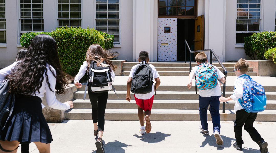 Kids running into school with their backpacks on