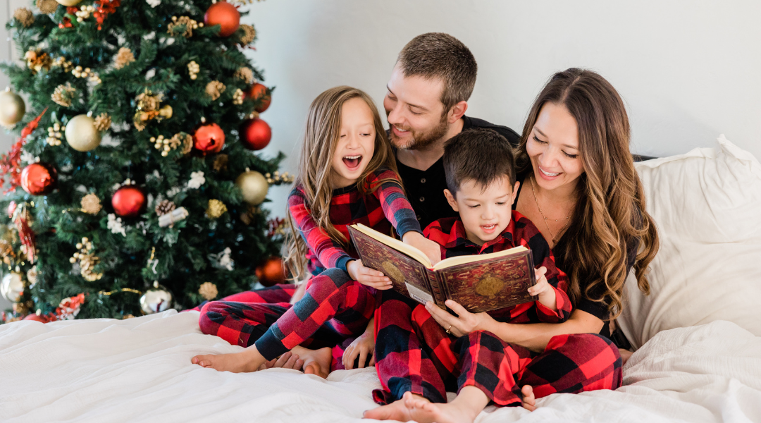 Family wearing matching pjs in bed by the Christmas tree